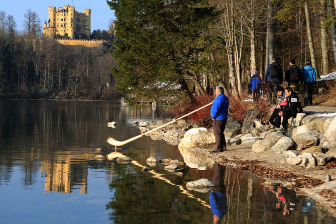 Thomas mit Alphorn am Alpsee, im Hintergrund ist das Schloss Hohenschwangau zu sehen_fotografiert von Marek Kowalski